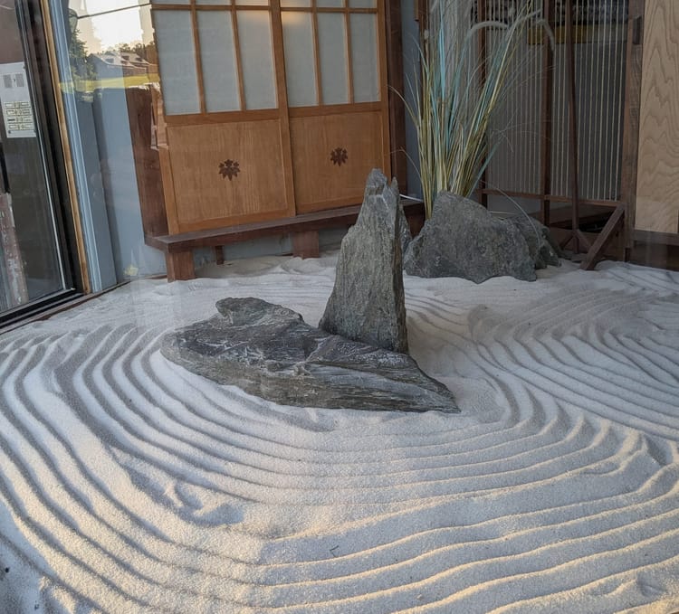 photo: zen garden: whorls of sand with slabs of rock in the middle